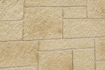 Close-up of a beige textured stone masonry wall with rectangular blocks and visible joints.