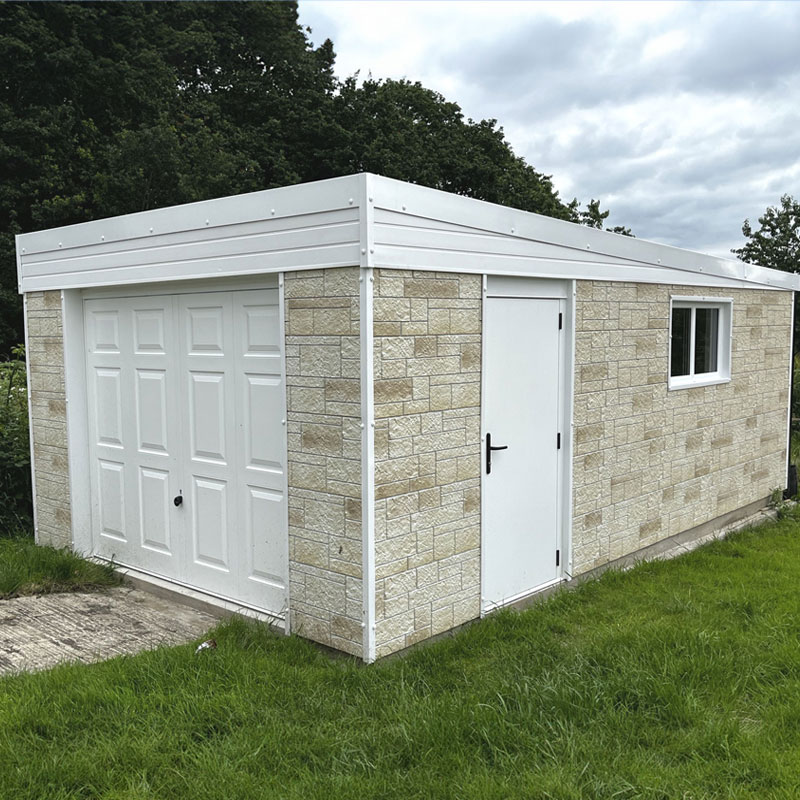 Stone outbuilding with a white double garage door, a white side entry door, and a small window on a grassy lawn under a metal roof.